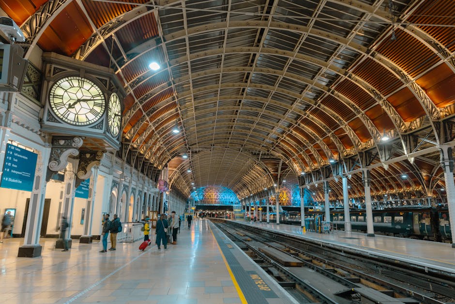 Interior view of Paddington Station showcasing a large, elongated glass and steel arched ceiling allowing natural light to illuminate the space. The platform features clean, polished floors with a smo